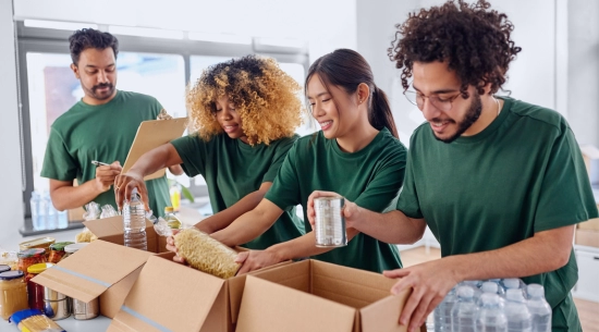 Four young people filling boxes with food. All four smile. 